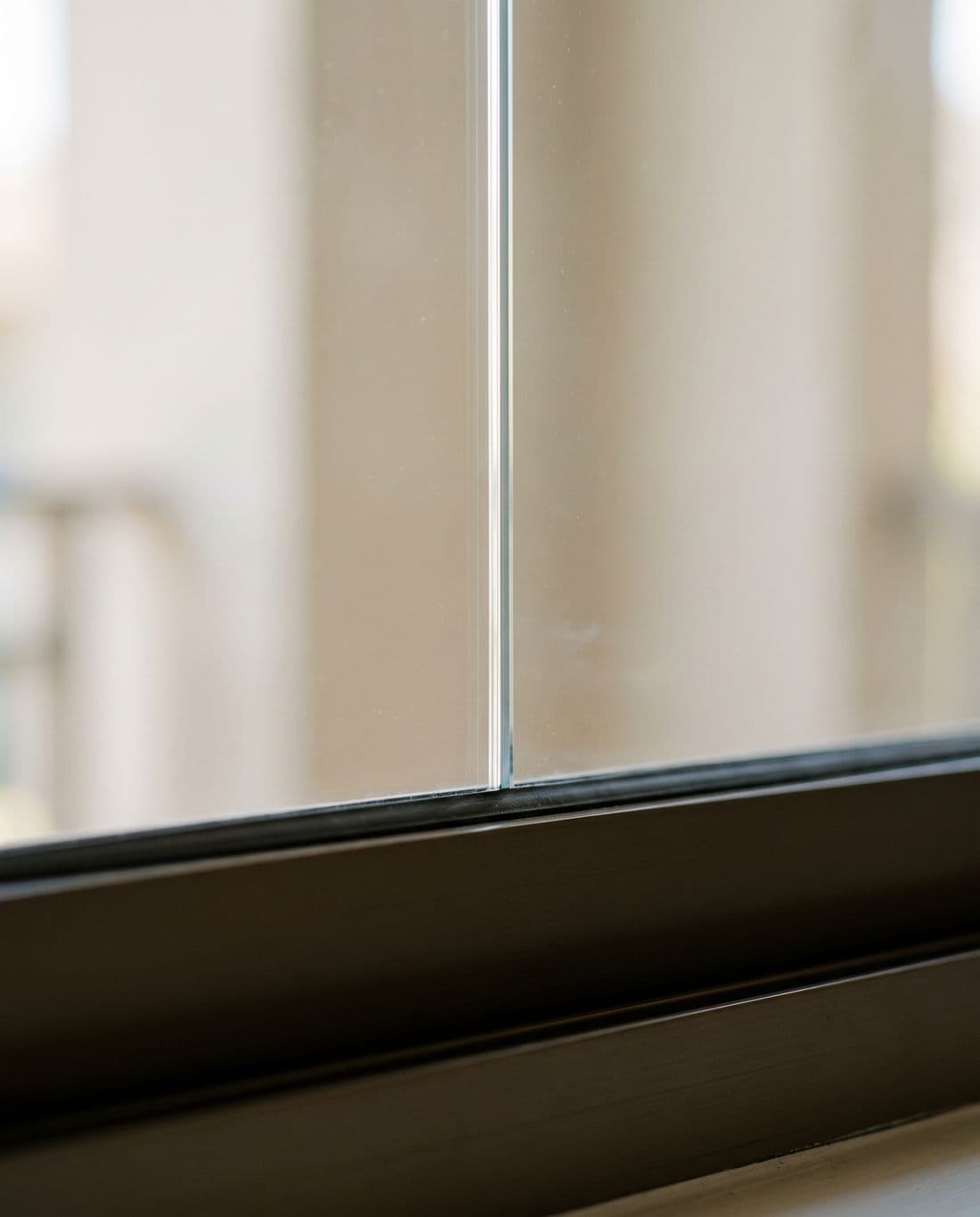 Extreme close study of the perimeter of an installed film where it meets the window frame: the cut line straight and tight, the surface clear, no bubbles or lifting